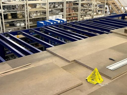 Blick auf eine Produktionslinie mit Holzplatten und gelbem Warnschild.